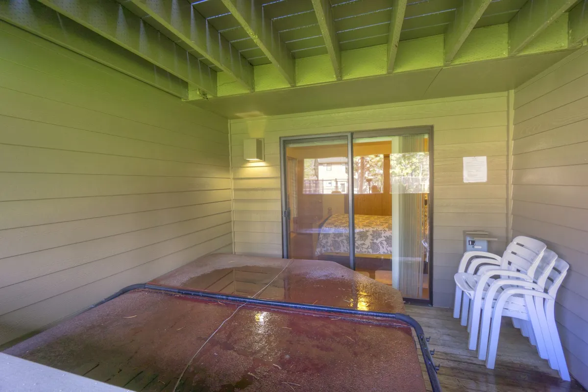 The image showcases a private hot tub on a patio, with nearby chairs and a sliding glass door opening to the outdoors. The setting is tranquil, ideal for unwinding after active days.
