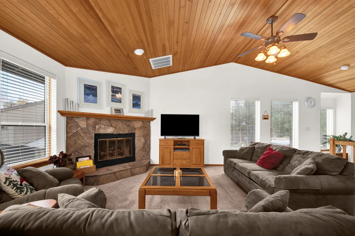 The image showcases a warm, inviting living room centered around a crackling fireplace, surrounded by plush sofas and a coffee table, perfect for cozy gatherings. The room is designed for relaxation and socializing, with a television for movie nights and ample space for family and friends to unwind together.