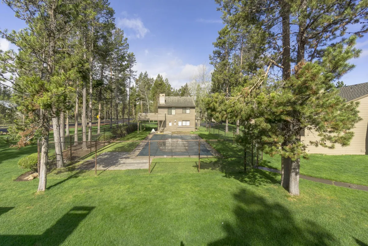This exterior image features the swimming pool surrounded by lush trees and the house in the background. The pool area is peaceful and inviting, capturing sunny afternoons ideal for family fun and relaxation.
