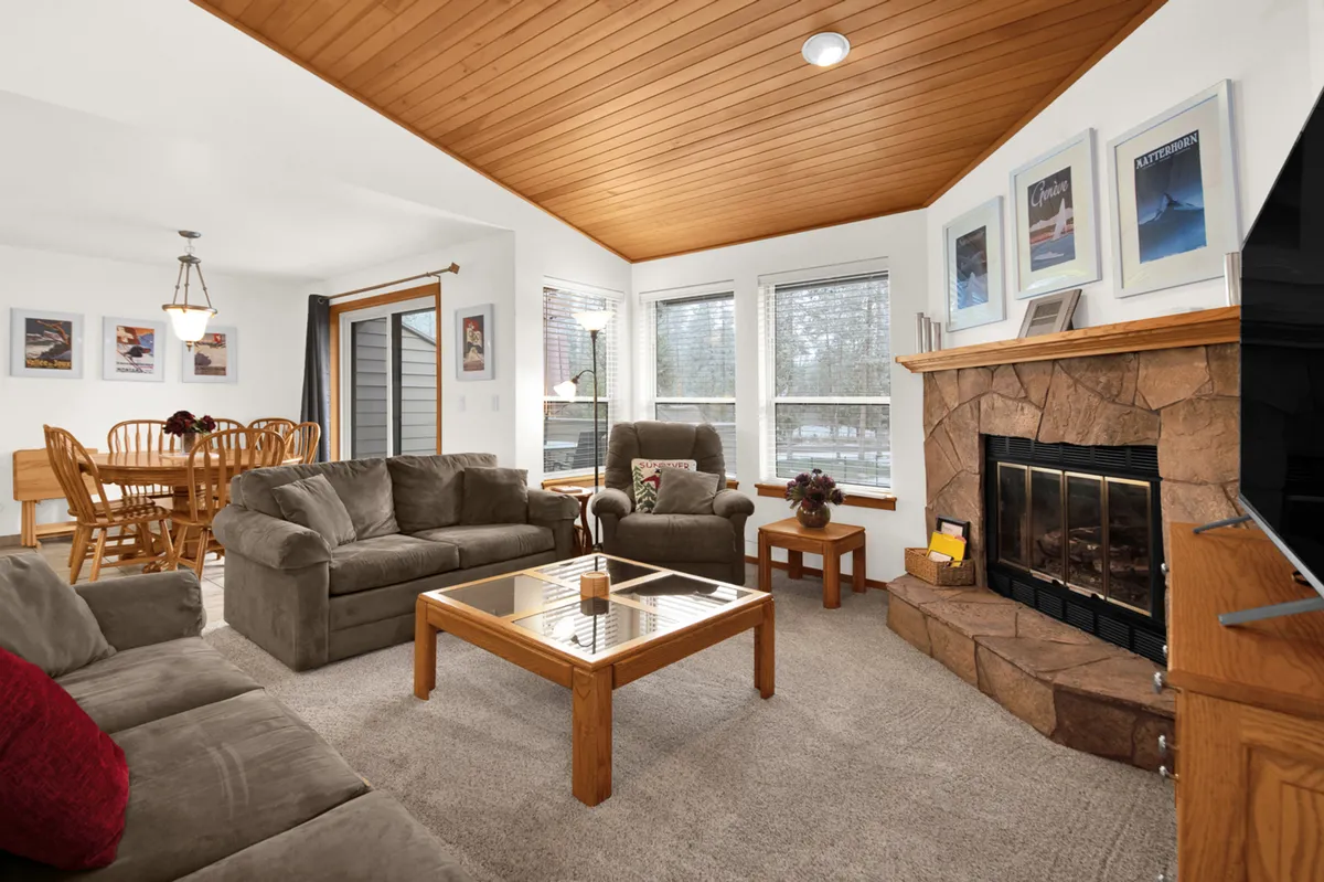 A cozy living area featuring a fireplace, comfortable sofa set, coffee table, and adjacent dining area. The space is designed for socializing and relaxing—perfect for unwinding after outdoor activities.