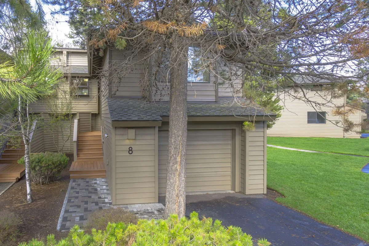 This exterior shot presents the home's inviting front entrance, a large tree shading the area, and serene landscaping. It hints at a warm welcome and the potential for outdoor gatherings or quiet moments.