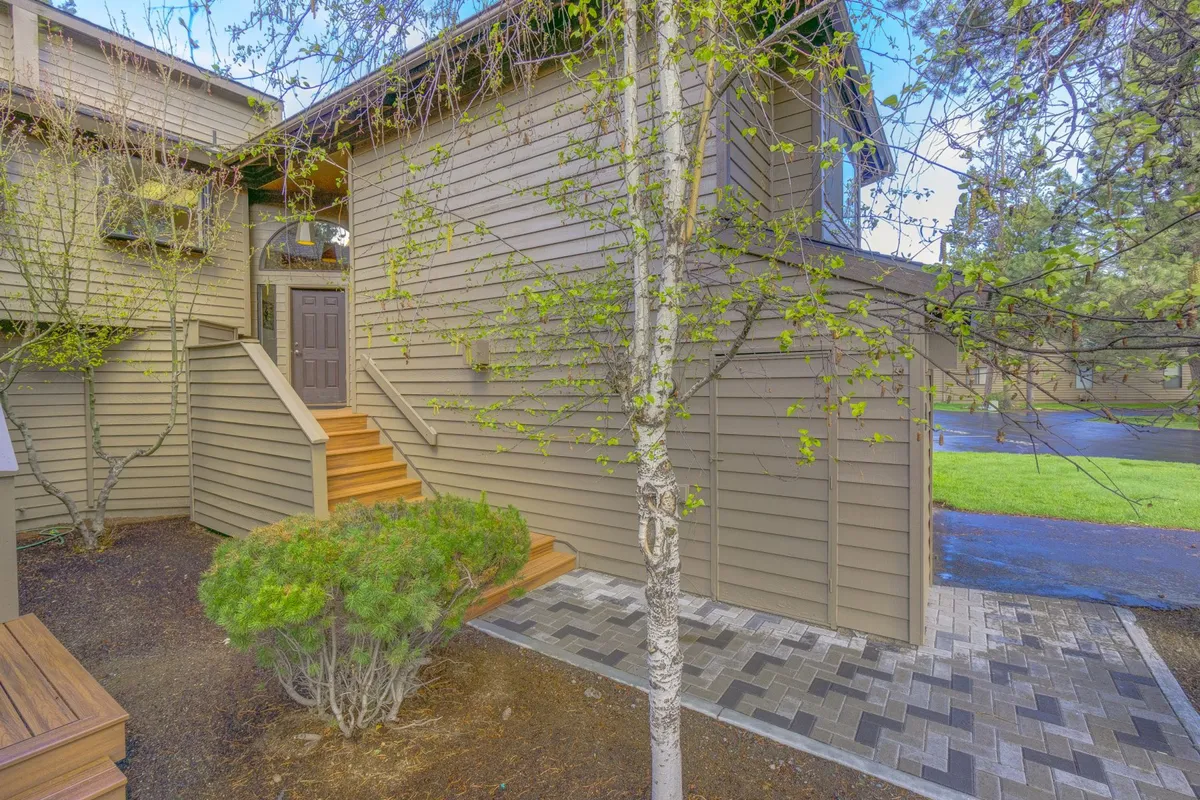 The image shows the exterior entrance steps leading up to the condo’s front door, bordered by a landscaped pathway and inviting greenery. The scene is bathed in natural light, offering a welcoming glimpse of the property’s outdoor setting and hinting at nearby outdoor amenities.