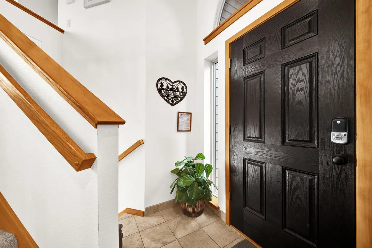 This image captures the condo's entryway with a front door, staircase, decorative heart plaque, and a touch of greenery from an indoor plant. The mood feels inviting, setting the tone for arrivals and departures as guests come and go for their Sunriver adventures.